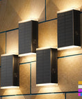 Four Pack Solar Wall Lights For Outdoor Use With Dusk To Dawn Sensor mounted on a textured wall, showcasing color options and glow.