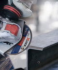 Close-up of Badass Torque 120 Volt 10 Amp X Lock Mount 4 1/2 Inch Corded Angle Grinder cutting steel with sparks flying.