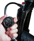 Hand holding Portable Bike Fork And Rear Shock Pump 400 PSI With 1.5 Inch Gauge Micro Air Adjust Button at bike fork valve