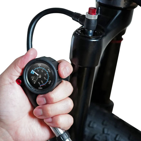 Hand holding Portable Bike Fork And Rear Shock Pump 400 PSI With 1.5 Inch Gauge Micro Air Adjust Button at bike fork valve