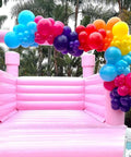 Rainbow Balloon Arch Kit With 80 Latex Balloons In 12 And 10 Inch Sizes Dope Neon Purple Teal Hot Pink Light Blue Light Green Matte Yellow And Lemon Hues Perfect Pool Party Vibes For Tropical Theme Carnival Decor For Kids Birthday over a pink inflatable bounce house.