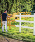 Pro Grade Airless Paint Sprayer With Fully Adjustable Pressure painting a white fence in a grassy area outdoors.