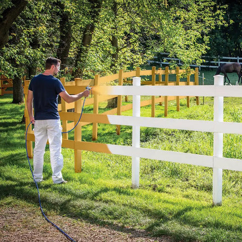 Pro Grade Airless Paint Sprayer With Fully Adjustable Pressure painting a white fence in a grassy area outdoors.