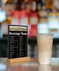 5x7 Inch Acrylic Sign Holder With Beech Wood Base For Vertical Or Slant Back Desk Display Perfect For Store Or Office Clear High Gloss Panel With Slick Wood Frame Durable Modern And Budget Friendly displaying beverage menu next to iced coffee