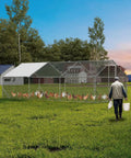 Person walking towards walk in chicken coop for hens with waterproof UV resistant cover and ventilated peaked roof in backyard.