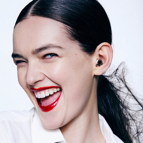 Person wearing Experience 2 Plus Ear Plugs For Concerts And Festivals With 17 dB Noise Reduction, smiling, close-up view.