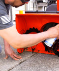 Person applying 6-16-TDL Advanced Dry Lube With Teflon 9.3 Oz Pack Of 6 to snowblower component, showcasing lubricant use on machinery.
