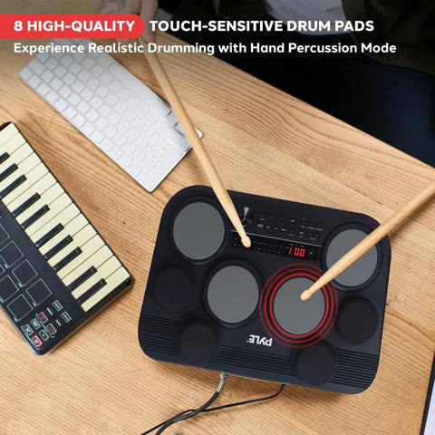 Compact Tabletop Electronic Drum Pad Kit With 8 Touch Sensitive Pads And Pedals on wooden desk with keyboard and sticks.