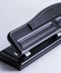 Side view of black adjustable two to three hole punch with padded handle, 11 sheet capacity for home or small office use on letter size docs.
