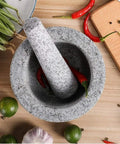 Top view of unpolished granite Mortar and Pestle Set with Lid, Two Cup Capacity, surrounded by fresh herbs and spices