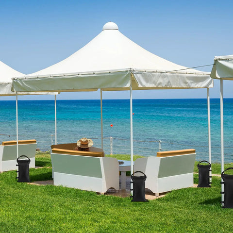 Heavy Duty Sand Bags For Canopy Legs Set Of 4 Empty Weight Bags beside pop-up tents by the ocean, securing shade structures.