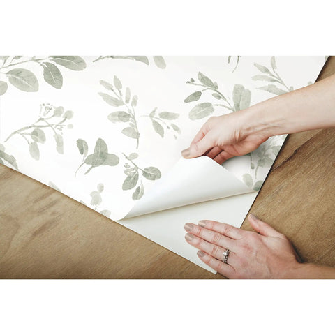 Hands peeling Dancing Leaves Peel And Stick Wallpaper Green And White for a quick easy wall makeover no glue needed removable