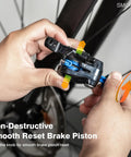 Hands using Bicycle Hydraulic Brake Caliper Spreader Tool for Mountain and Road Bikes on a disc brake.
