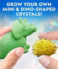 Hands holding green dinosaur and yellow mini crystal from Five Types Crystal Growing Kit With Glow In The Dark Crystal Dinosaur Figure Underwater Crystals And Crystal Trees Plus Learning Guide A STEM Science Kit For Kids Totally Fun And Educational