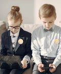 Children sitting with digital devices wearing buttons from the Bulk 400 Piece Button Making Kit No Brainer With Fifty Eight Millimeter Button Parts