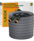 GUKOK 100 ft non-expanding garden hose, gray braided exterior with brass connectors, coiled beside box.