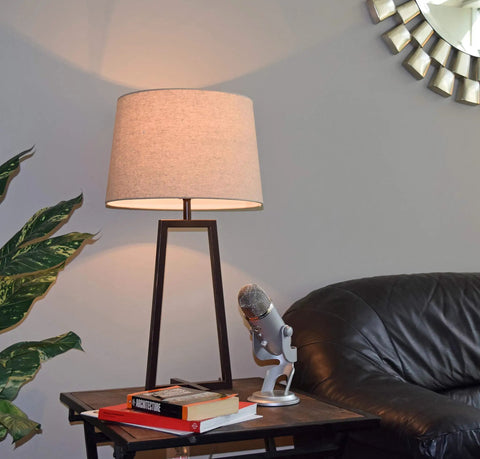 Tall Mid Century Modern Table Lamp With Oil Rubbed Bronze Finish And Open Frame, Tapered Oatmeal Drum Shade on table