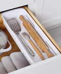 Expandable Sliding Drawer Bin For Kitchens Sets The Bar Inside Deep Drawers with utensils and towels organized in speckled white.