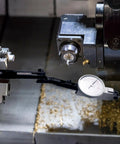 Dial indicator holder with adjustable 3-pivot axial arm and dial gauge mounted on a metal lathe.