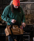 Person holding Trade Series 16 Inch Tool Bag with Zippered Main Compartment and 23 Pockets in a workshop setting