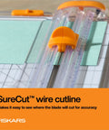 Precision Paper Trimmer With SureCut Wire Cut Line And TripleTrack System cutting green paper, clear rail for accuracy.