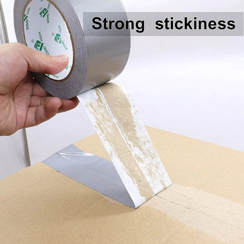 Applying Heavy Duty Duct Tape 2 Pack 9 Mil Thick 2 Inch By 30 Yards Waterproof No Residue Flexible Repair Tape on cardboard surface.