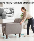 A woman using Four Pack Mini Swivel Caster Wheels With Secure Locking Brake And Heavy Duty Self Adhesive Backing For Dead Simple Peel And Stick Install On Office Chairs Desks Or Rolling Storage Carts to easily move a gray armchair.