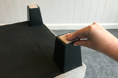 No Sweat Top Tier 2 Inch Square Furniture Sliders With Self Adhesive Backing on furniture leg, showing beige glides for easy movement.