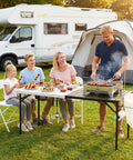 Family enjoying BBQ using 5ft Folding Camping Table With Dual Surface Metal Grill Grid And Solid Prep Top Heavy Duty Portable Outdoor Table.