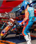 Motocross rider in blue and orange gear tuning dirt bike on A2 Motocross Aluminum Dirt Bike MX Stand