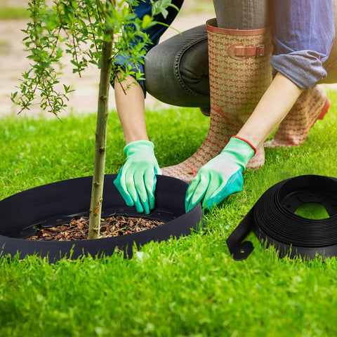 Person installing 148 Ft Garden Landscape Edging Kit With 4 Inch Tall Border Easy Install DIY Friendly Includes 70 Spiral Anchors And 20 Connectors Black Border Roll For Walkways Flower Beds Lawns And Yard Decor around tree with gloves.