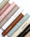 Rolled Double Sided Two Tone Faux Leather Desk Mats in various colors, including Beige and Brown, arranged side by side.