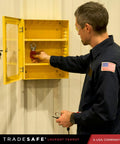 Man using a Lockout Tagout Cabinet For Unfilled Station Wall Mountable LOTO Box Industrial Grade 19 Gauge Steel With Durable Shackle Holders No Devices Included Heavy Duty Lockout Center For Safe Equipment Lockouts mounted on a wall.