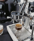 Next Level Home Bar Essentials Italian Handcrafted Espresso Machine With Heat Exchanger And E61 Manual Controls Badass Stainless Steel Chassis Three Liter Tank Fresh White Finish close-up of espresso brewing with stainless steel components.