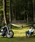 Man relaxing next to motorcycle with Bug Free Camping Hammock With Mosquito Net suspended in forest