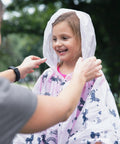 Child wearing a Disposable Rain Ponchos Family Pack Eight Pack With Hood For Adults And Kids Waterproof Emergency Travel Ponchos