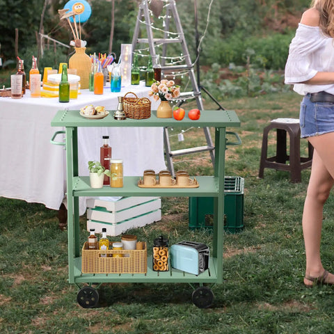 Flat Out Sturdy Three Tier Rolling Kitchen Cart Slick Green Metal Server with beverages and snacks in outdoor setting.