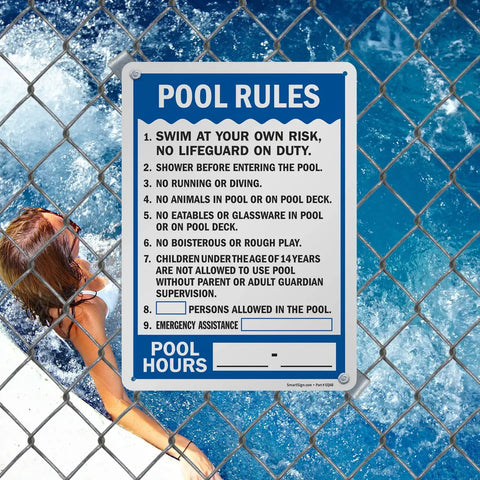 Pool Rules Sign 14 By 10 Inch Write On Aluminum With Four Corner Mount Holes Swim At Your Own Risk Shower Before Entering Emergency Assistance Pool Hours 40 Mil Laminated Heavy Duty Weatherproof Outdoor USA Made displayed on a chain link fence by a pool.