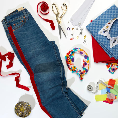 Craft setup with jeans, scissors, and Fabric Fusion Glue 4 Ounce Permanent And Washable No Sew Fabric Glue For Clothing Denim Cotton Polyester And Flannel Dries Flexible For Quick Repairs Crafts And Alterations
