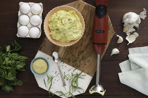 No Fuss Hand Immersion Blender With Attachable Whisk Piece 2 Speed 250 Watt Motor Dishwasher Safe Kitchen Game Changer For Quick Meals And Smooth Blends In Bold Red on a wooden countertop with blending ingredients.