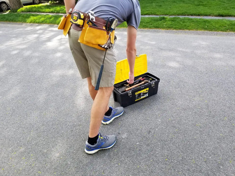 Person wearing 11 Pocket Suede Leather Heavy Duty Tool Belt Built Tough For Pros with hammer loops and measuring tape, adjusting toolbox