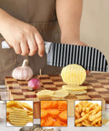 Side view of OLULU crinkle cutter knife with rubber handle; ridged stainless blade slicing potato on cutting board
