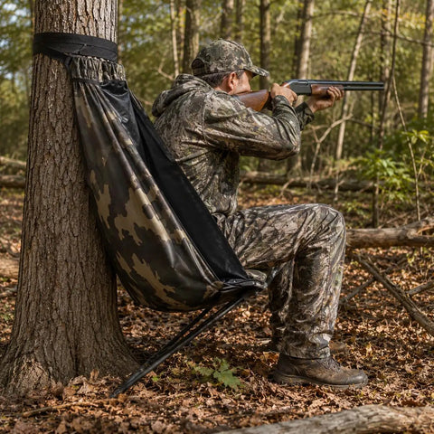 Hunter using Low Profile Hunting Chair Hammock Seat With 360 Degree Swivel Portable Camouflage Ground Stool for deer in the woods