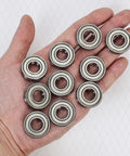 Heavy duty ball bearings 6205 ZZ in hand, set of 10, showcasing double metal shielded design for machinery and automotive use.