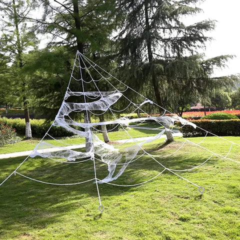Large outdoor spider web decoration made with ropes and circular anchors on grass, resembling a giant web structure among trees.