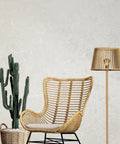 Ivory And Off White Rose Gold Cracked Faux Concrete Plaster Textured Wallpaper Rolls Chic Home Decor Peel And Stick Removable Wall Covering DIY Project in modern living space with rattan chair and floor lamp.