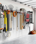 Wall Mount Garden Tool Organizer And Garage Space Saver Storage Rack For Shovels Rakes Brooms Ladders And Folding Chairs Keep Your Space Clutter Free With Keyhole Shelving Compatibility And Easy Hanging Hooks installed on a garage wall with tools and equipment hanging.