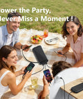 People using 20000mAh Solar Power Bank With Wireless Charging Built In Cables And 15W USB C Fast Charging Charge Up To Six Devices At Once Compatible With iPhone And Samsung Emergency LED Flashlight Ideal For Camping And Hiking outdoors on a picnic table.