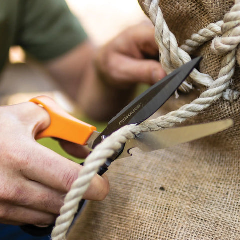 Close-up of All In One Garden Tool 7-In-1 Pruning Shears cutting rope, showcasing titanium knife in action on a burlap sack.