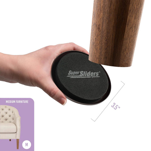 Hand holding a 3.5-inch reusable furniture slider for carpet, showing placement under wooden furniture leg, black color, 4-pack.